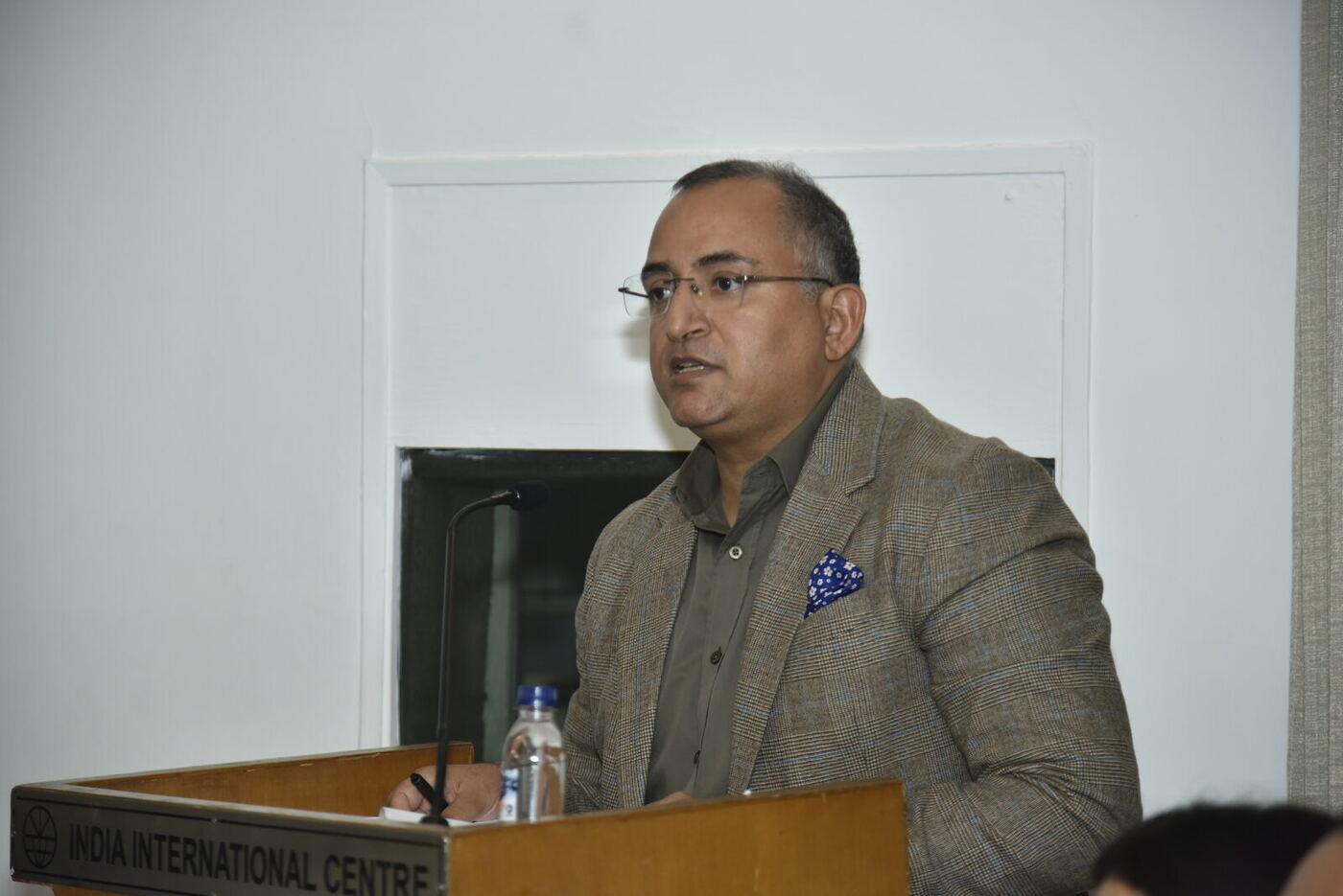 Moderator speaking at the IIC lectern, nameplate legible