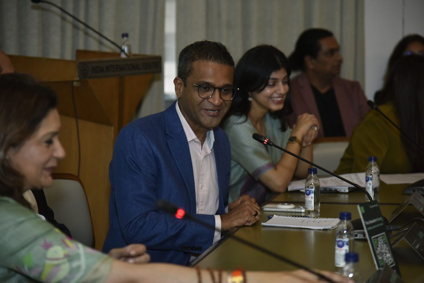 Jaivir Singh smiling mid-answer, young woman in mint laughing behind him
