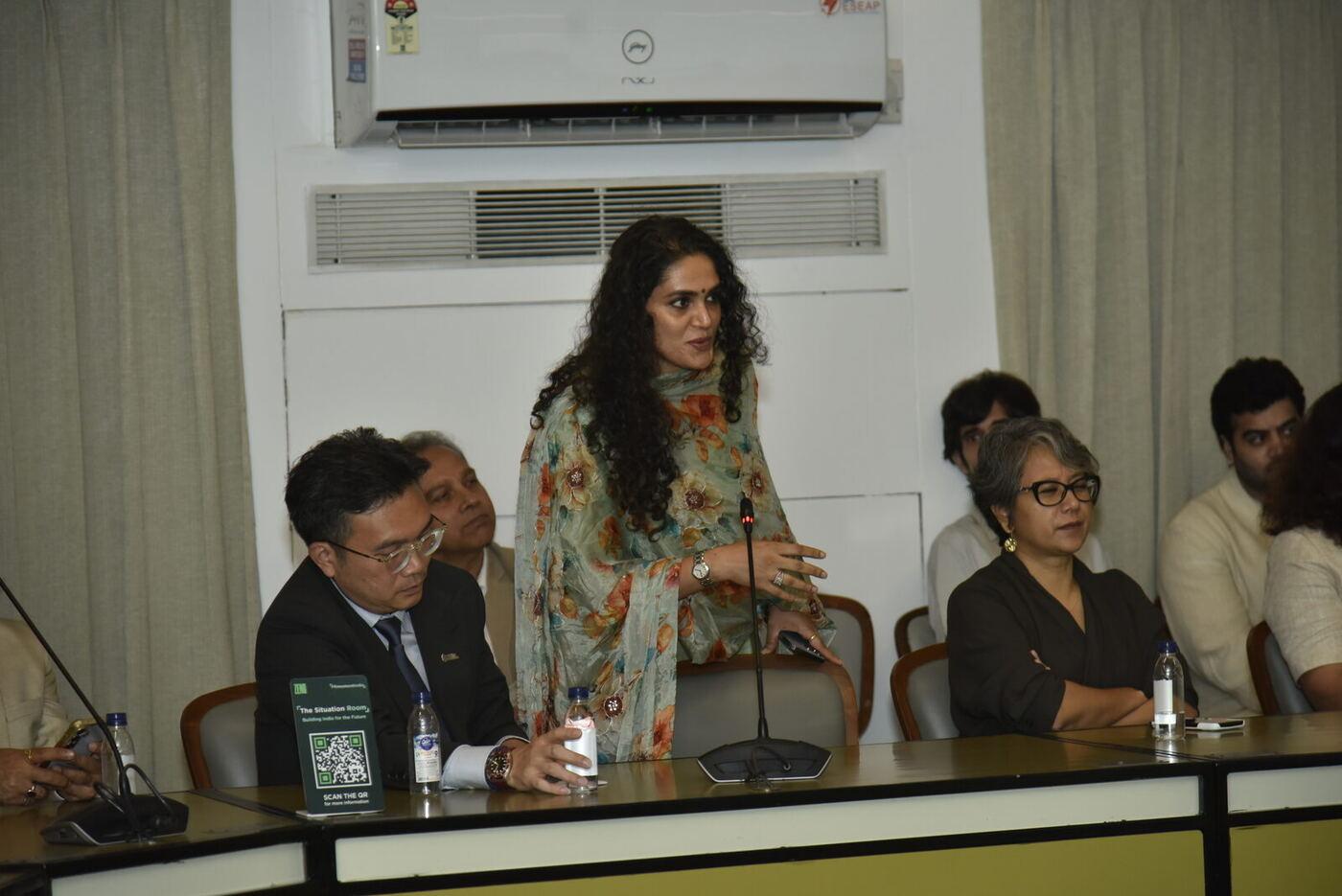 Woman in a floral dupatta standing at the mic to ask the first question