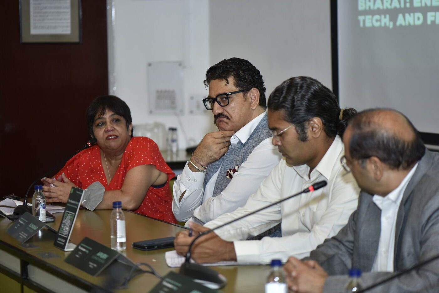 Paarul Chand in red putting a question, three male panellists listening