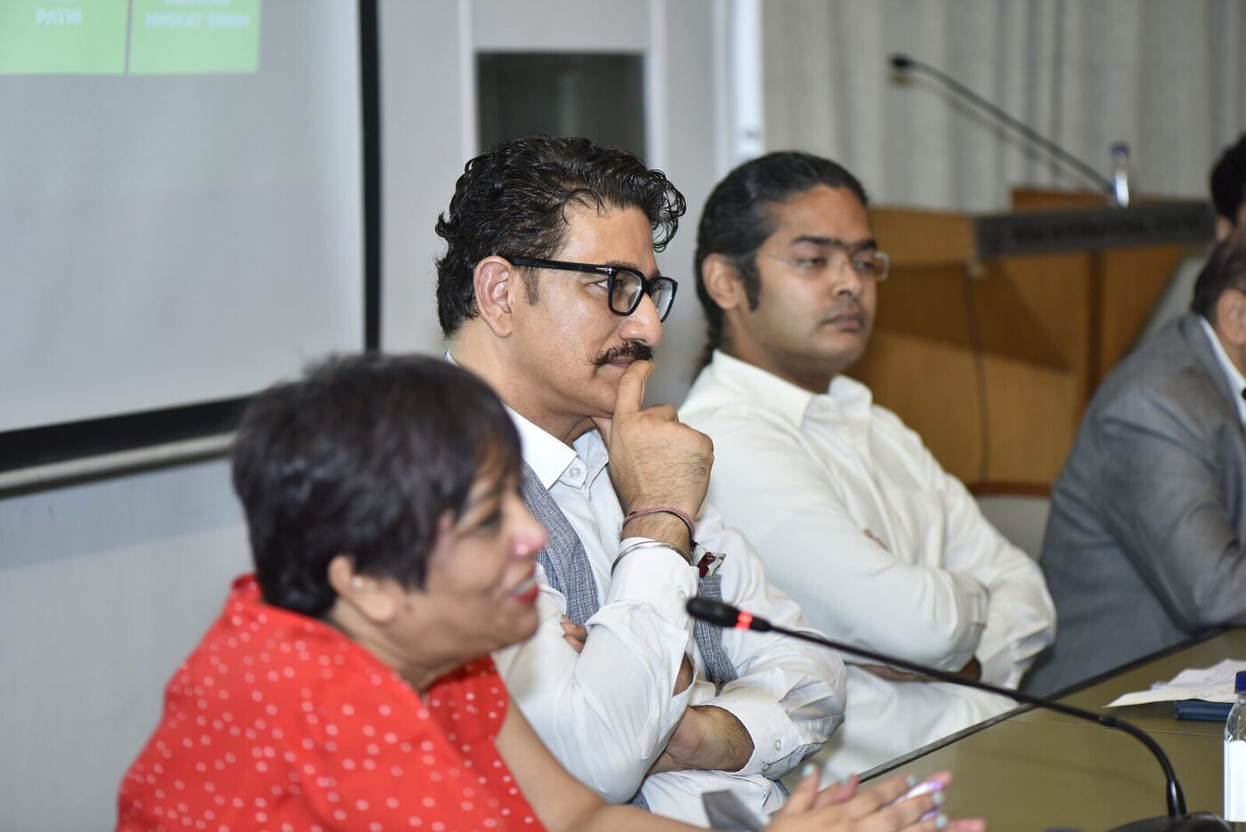 Kunwar hand on chin listening as the moderator laughs at the far end